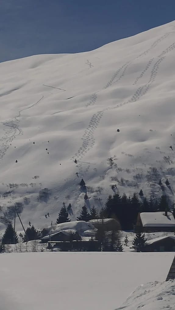 Verschneiter Hang mit Skitourenspuren im Tiefschnee oberhalb der Maiensäss-Häuser von Radons