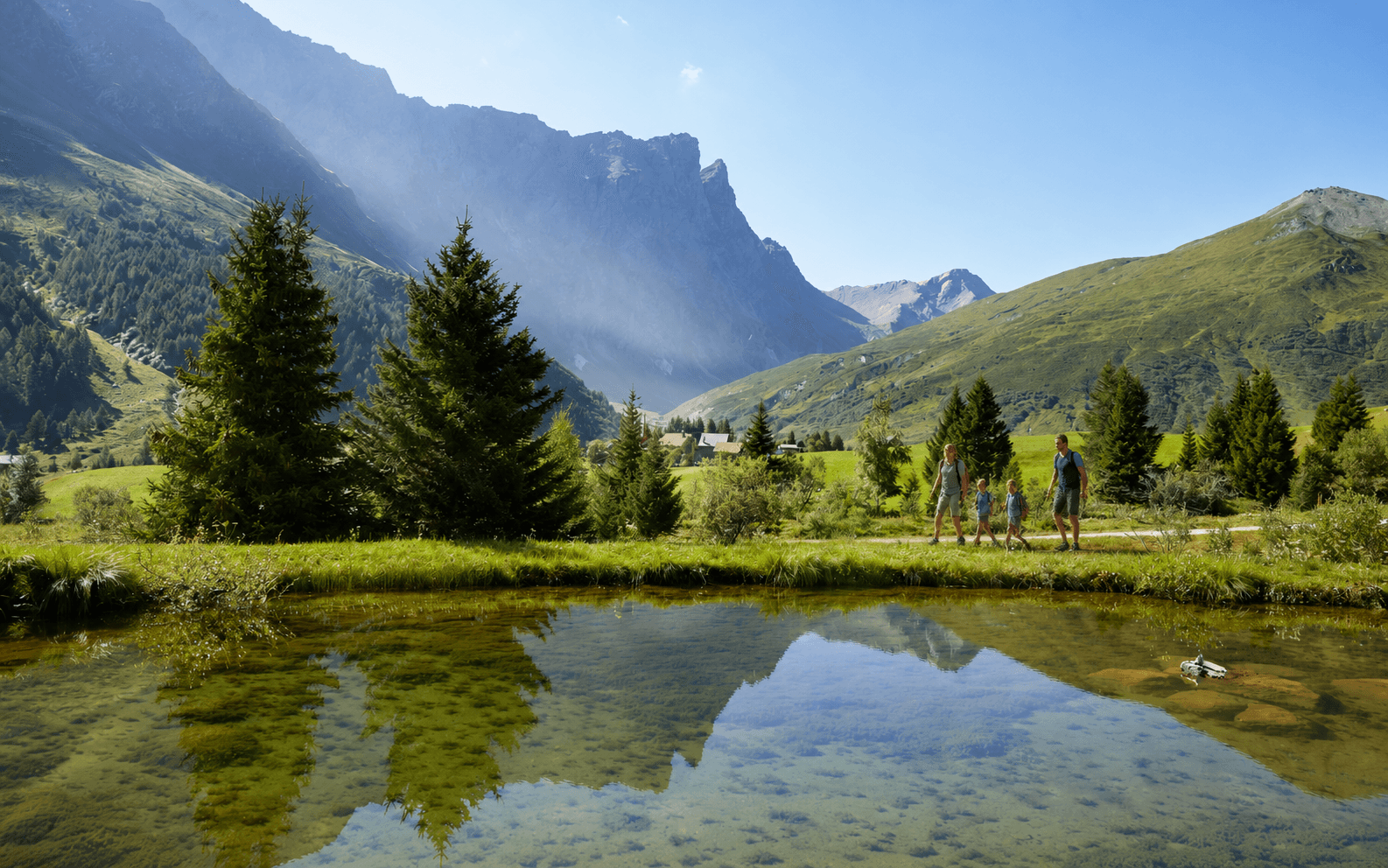 Familie auf einem Sommerweg an einem Bergsee bei Radons mit Bergpanorama
