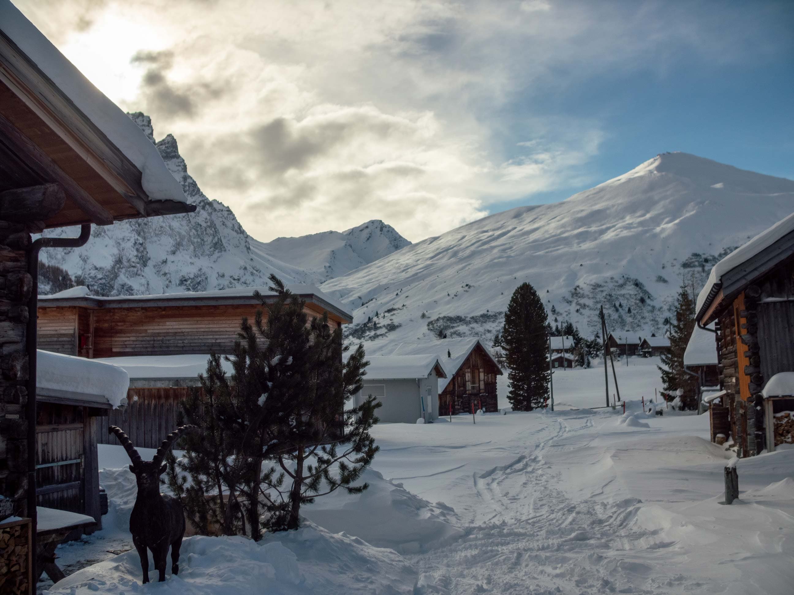 Maiensäss seitlich mit verschneitem Tal im Winter